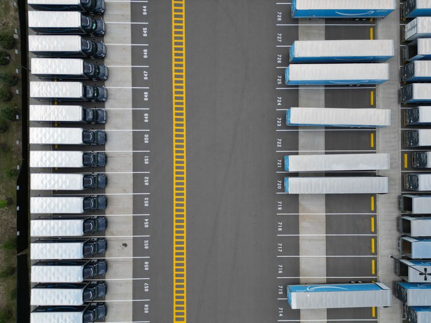 Top-down view of lined-up trucks at a logistics parking lot, showing organized transportation hub.