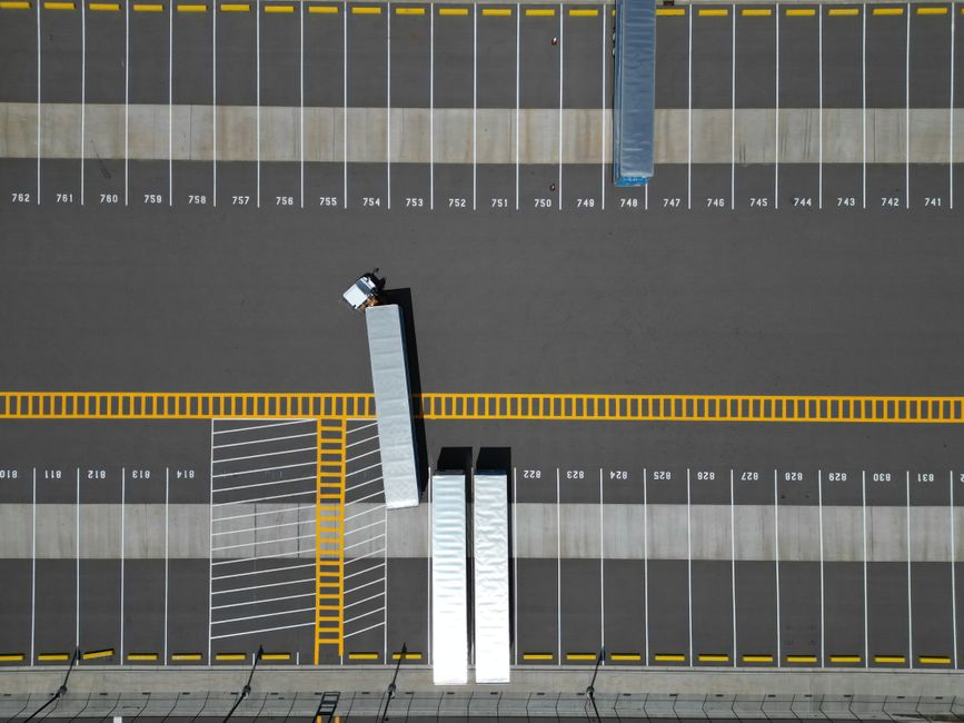 An aerial view of a large parking lot with lined spaces and semi-trucks.